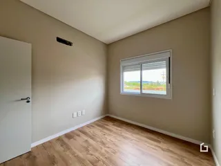 Foto de um cômodo interno com piso de madeira clara e janela.