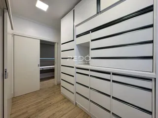 Corredor com armários embutidos brancos e piso de madeira clara.