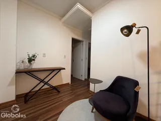Foto de uma sala de estar com piso de madeira e paredes brancas.