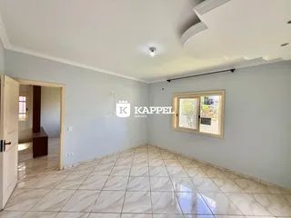 Sala ampla com piso de porcelanato claro e paredes em tom de azul claro.