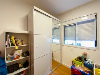 Quarto com armários e estantes brancas em um imóvel no Brasil.