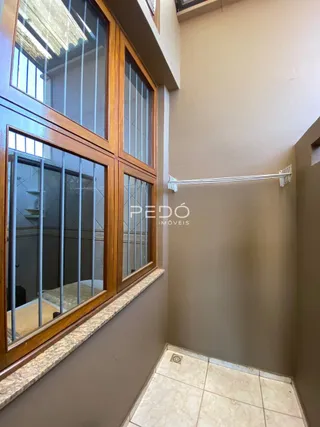 Vista interna de um corredor com janelas de madeira e piso de cerâmica.