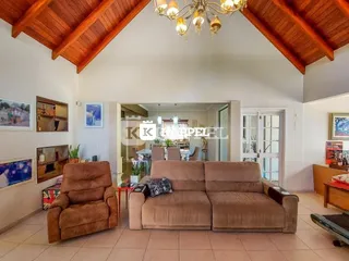 Sala de estar com sofá marrom e vigas de madeira expostas no teto.