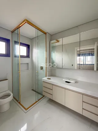 Foto de um banheiro com box de vidro e piso de mármore branco.