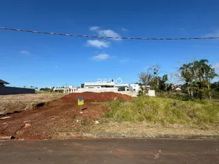 Foto da paisagem externa de um terreno com vegetação e construções ao fundo.