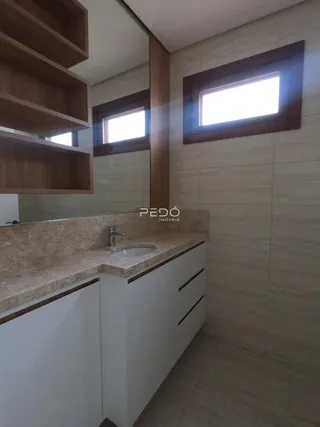 Vista de um banheiro com bancada e armários brancos.
