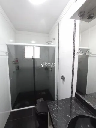 Interior de um banheiro com box de vidro e revestimento cerâmico.