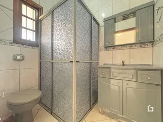 Foto de um banheiro com revestimento de cerâmica e box de vidro.