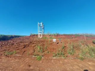 Paisagem de terra vermelha e vegetação rasteira em uma área aberta.