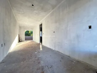 Corredor interno com paredes brancas e piso de concreto.