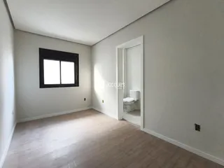 Vista interna de uma sala com piso de madeira e janela.