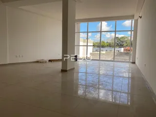 Interior de um espaço amplo com piso de porcelanato e grande janela.