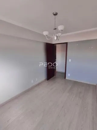 Vista interna de um ambiente com piso de madeira clara e parede branca.
