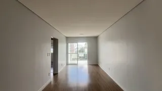 Hall de entrada com piso de madeira e paredes brancas.