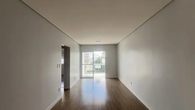 Hall de entrada com piso de madeira e paredes brancas.