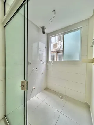 Foto de um banheiro com revestimento cerâmico branco e box de vidro.