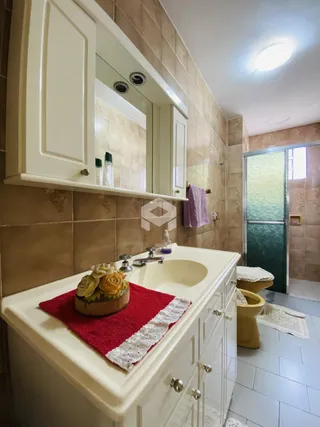Foto de um banheiro com bancada branca e revestimento de parede bege.