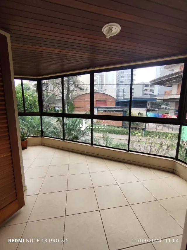 Vista interna de uma sala com grandes janelas que dão para o exterior.