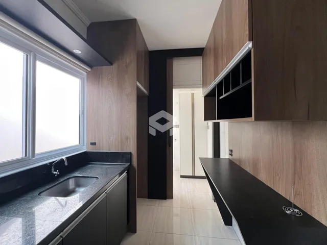 Vista da cozinha com armários de madeira e bancada escura.