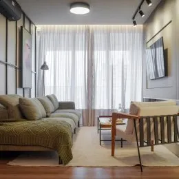Quarto com cama e cortinas claras em ambiente interno.