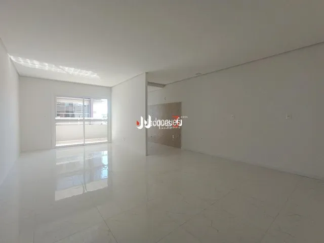 Interior de um ambiente claro e vazio com piso branco e grande janela.