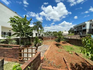 Vista externa de um terreno com muros de tijolo e vegetação.