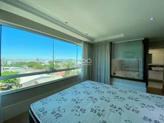 Quarto com grande janela oferecendo vista para a paisagem urbana.