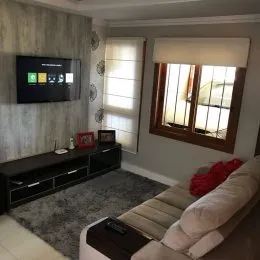 Uma sala de estar com televisão e móveis escuros é visível na propriedade.