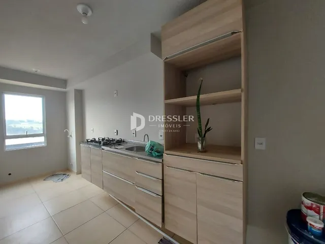 Vista interna de uma cozinha com armários e piso claro.