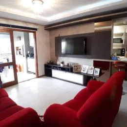 Sala de estar com sofá vermelho e piso claro.