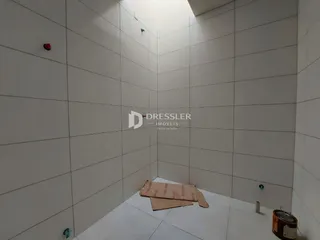 Hall de corredor interno com paredes brancas e piso de cerâmica.