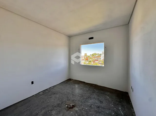 Imagem de um cômodo vazio com paredes brancas e piso de concreto no imóvel.