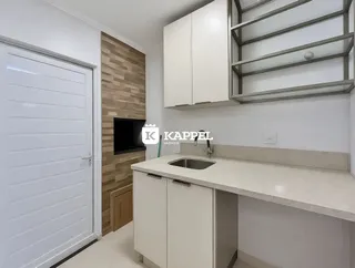 Uma cozinha moderna com armários brancos e bancada clara.