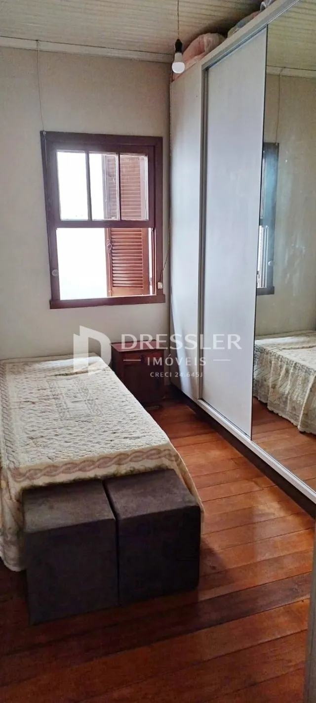 Foto de um quarto com piso de madeira e janela em uma residência.