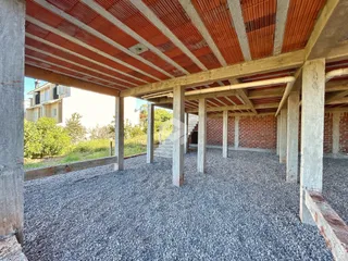Vista de uma área externa coberta com piso de cascalho e estrutura de concreto.