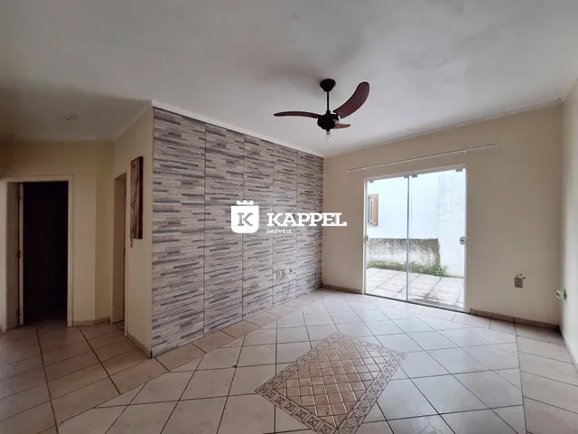Sala de estar com piso de cerâmica e parede revestida em azulejos cinzas.