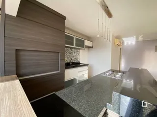 Sala de estar com painel de madeira e área de cozinha moderna.
