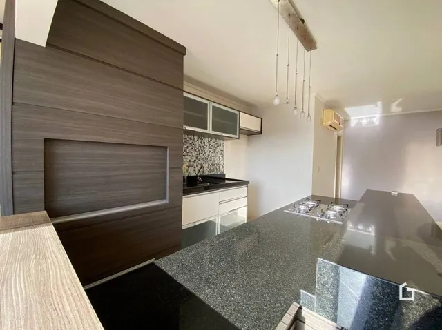 Sala de estar com painel de madeira e área de cozinha moderna.