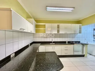 Uma cozinha com armários brancos e bancadas escuras.