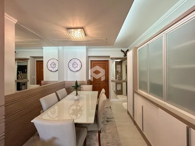 Vista de uma sala de jantar com paredes claras e móveis de madeira.