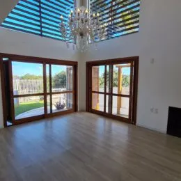 Sala de estar com grandes janelas de madeira que dão para o exterior.