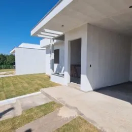 Fachada branca de uma residência com portico e área externa.