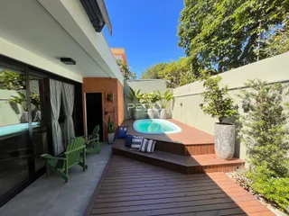 Vista da área externa com piscina e deck de madeira.