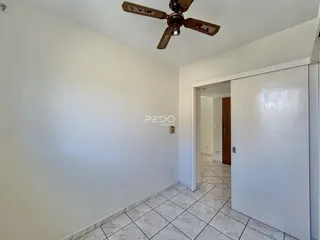 Interior de uma sala com paredes brancas e piso de cerâmica clara.