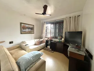 Sala de estar com sofá e televisão em um imóvel no Brasil.