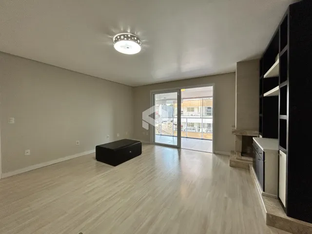 Ambiente interno de uma sala de estar com piso de madeira clara e portas de vidro.