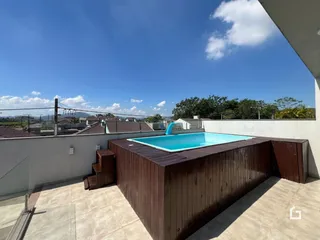 Vista de uma piscina e deck de madeira em uma propriedade no Brasil.