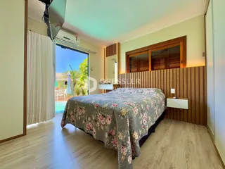 Quarto com cama e porta de vidro abrindo para a área externa.