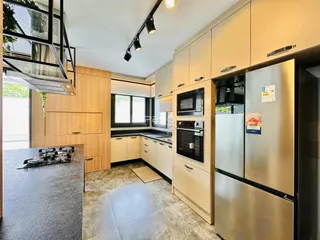 Vista da cozinha moderna com armários em madeira e eletrodomésticos de aço inoxidável.