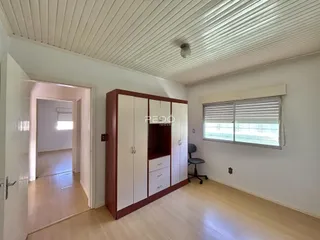 Interior de uma sala com piso de madeira e armário embutido.